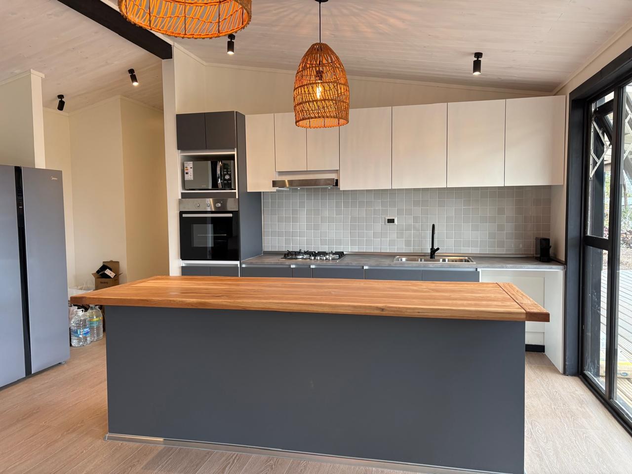 Cocina a medida con muebles altos claros, isla con cubierta de madera y base gris