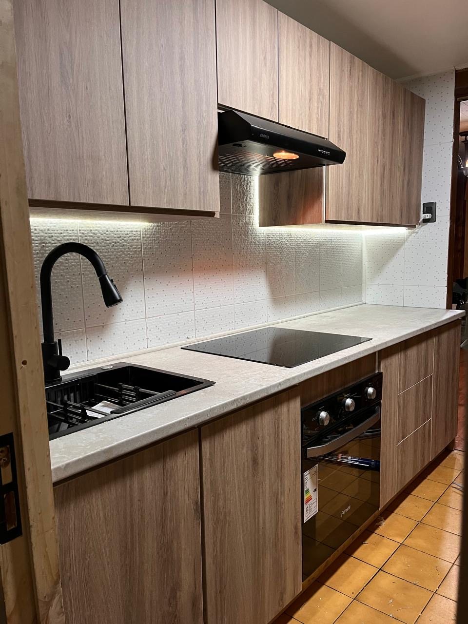 Después: cocina moderna con melamina tono madera, iluminación LED y grifería negra
