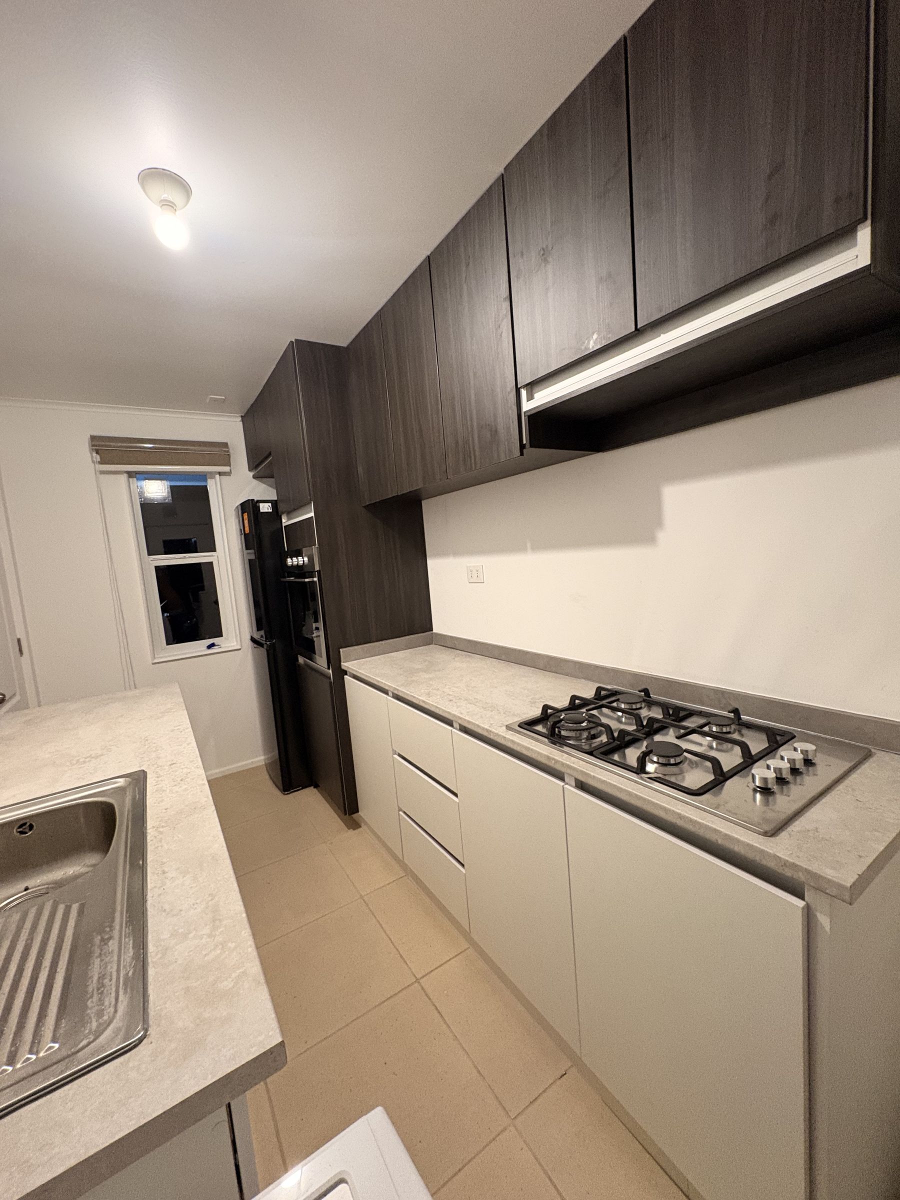 Cocina moderna con muebles altos oscuros, base clara y cubierta tipo hormigón