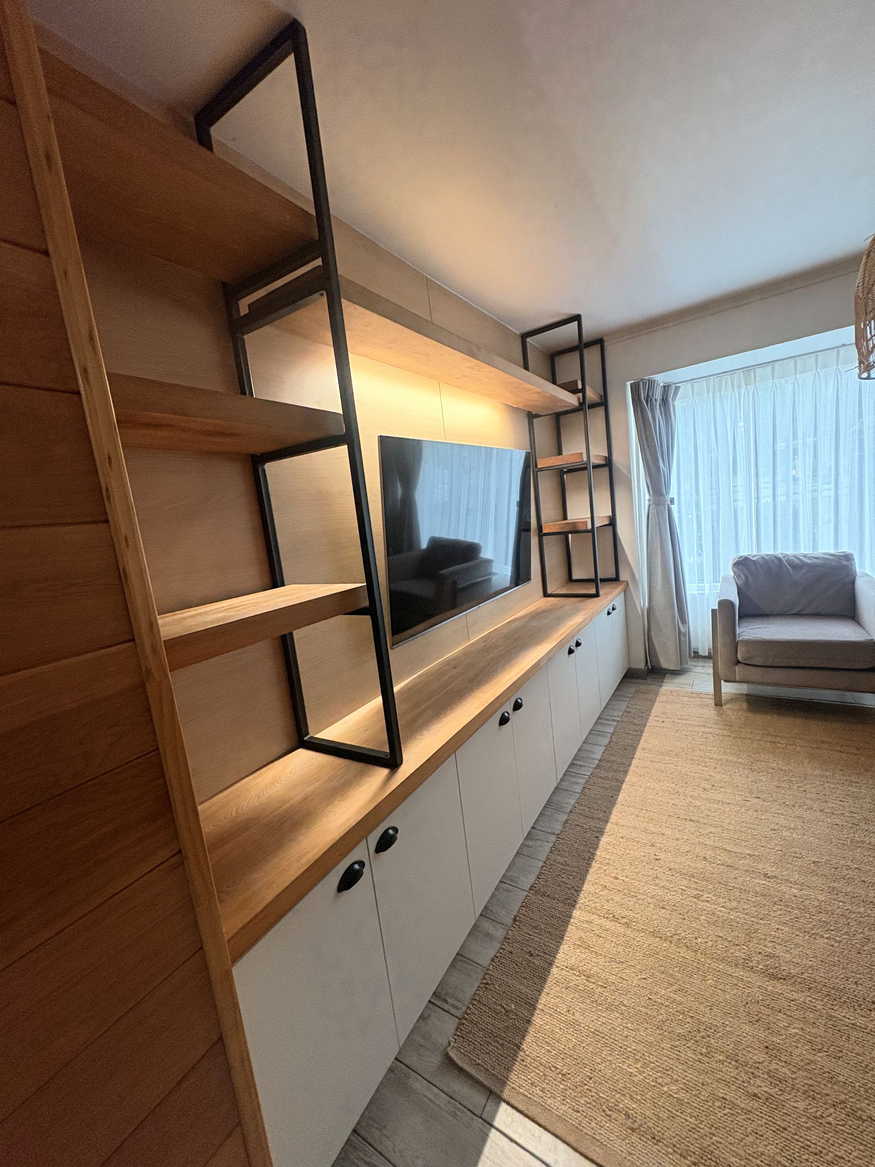 Mueble de living con repisas de madera, estructura negra e iluminación LED